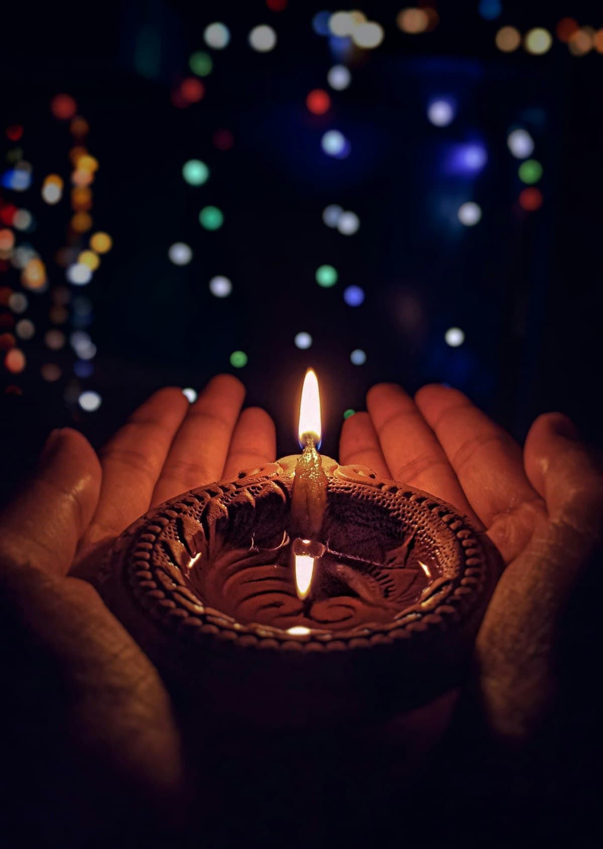Diwali diya held in hands with bokeh lights background — festival of lights 2026