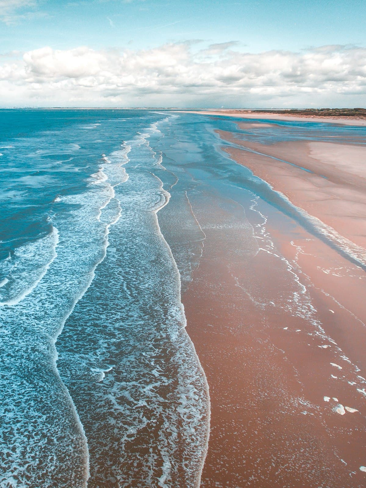 Aerial view of pristine beach shoreline with turquoise waves and tan sand — Labor Day 2026 NRI getaway