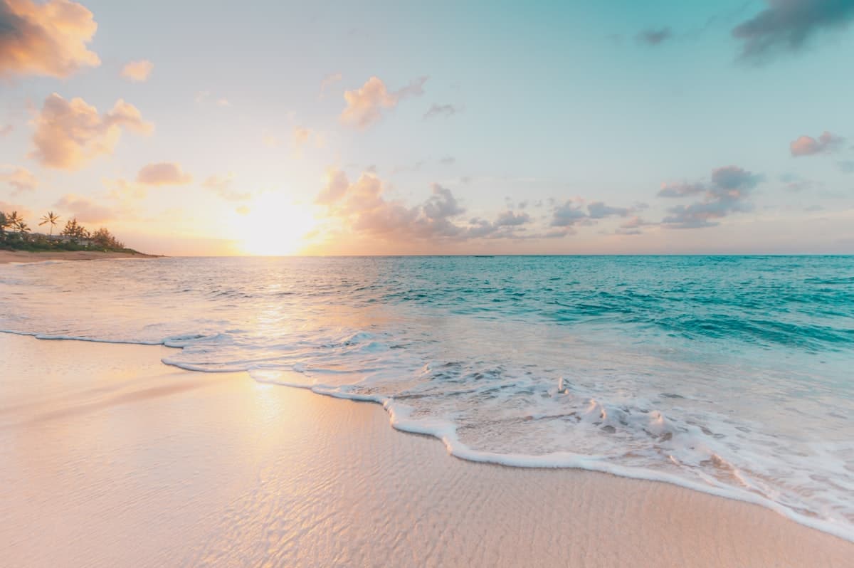 Sunset over tropical beach with sand and turquoise water — Labor Day family vacation vibe
