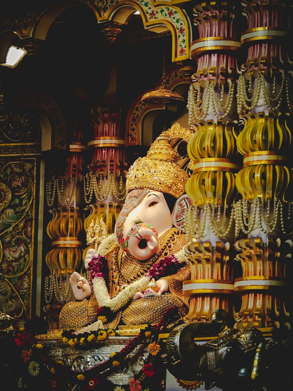 Ganesha idol in traditional decorated shrine with hanging garlands — Ganesh Chaturthi 2026